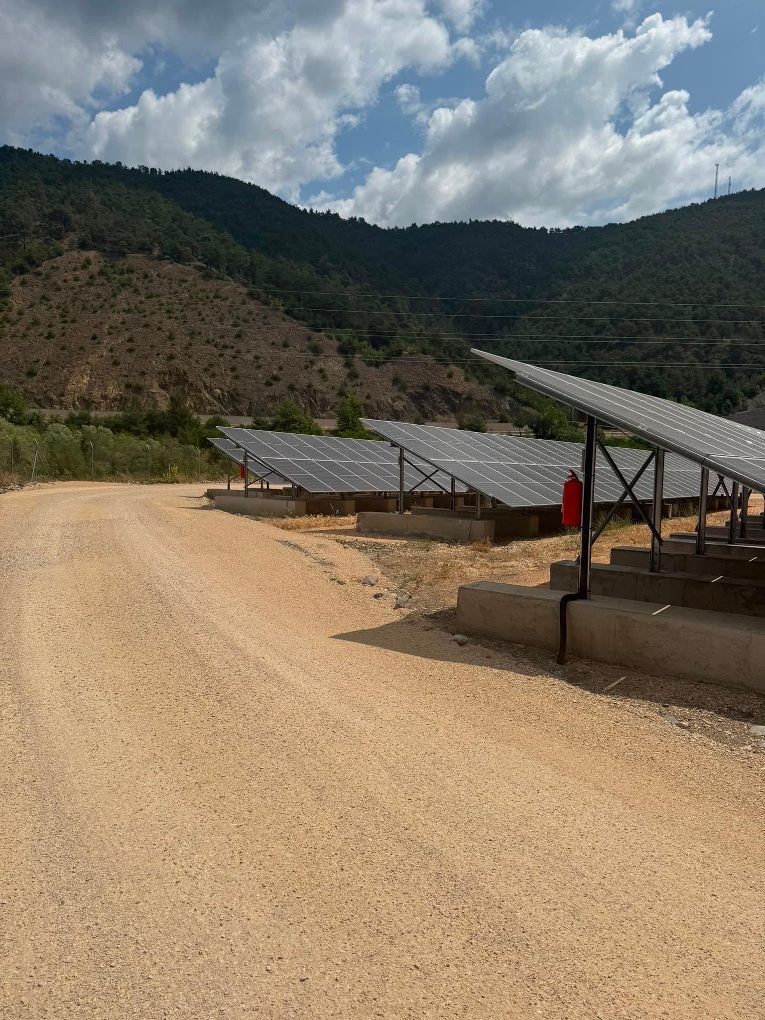 Güneş enerjisi santrali sahasında panel sıraları ve saha yolu